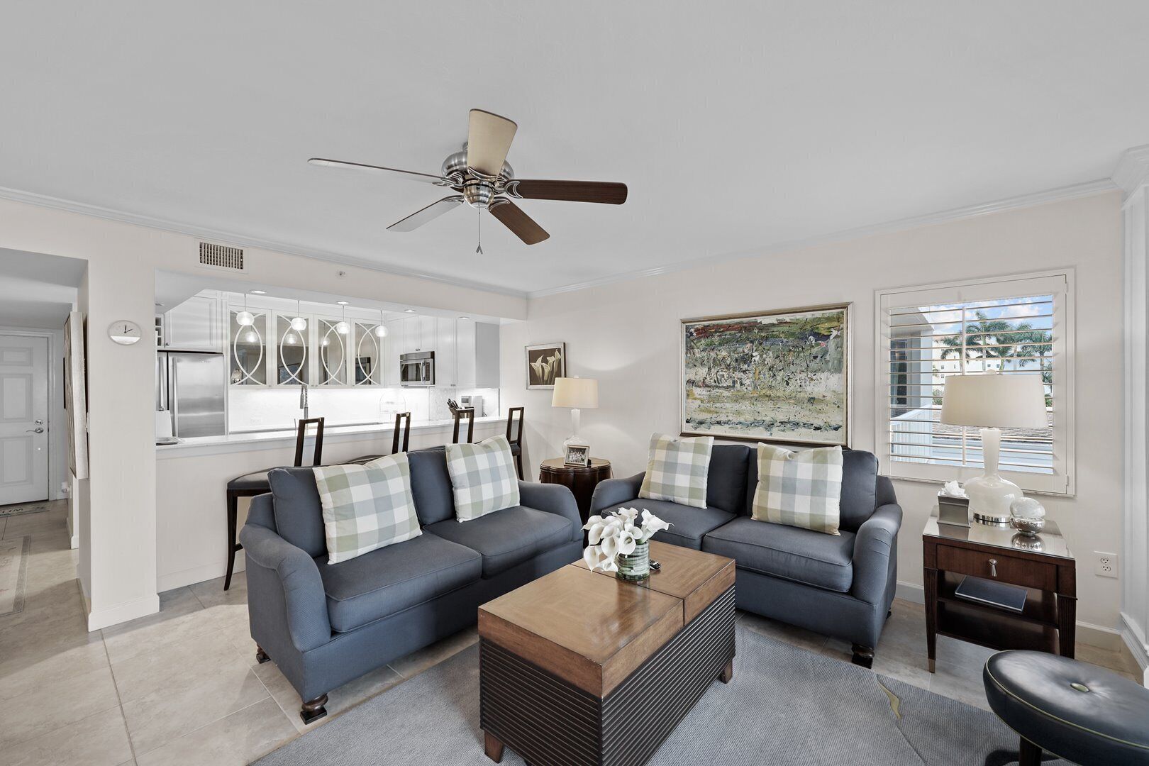 A modern living room with two sofas, a coffee table, and a ceiling fan.