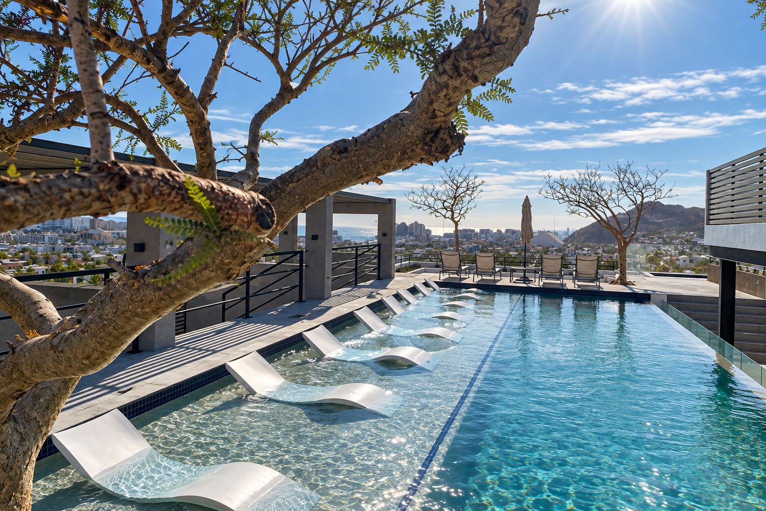 A swimming pool with a clear blue water feature, surrounded by lounge chairs and a view of a cityscape.