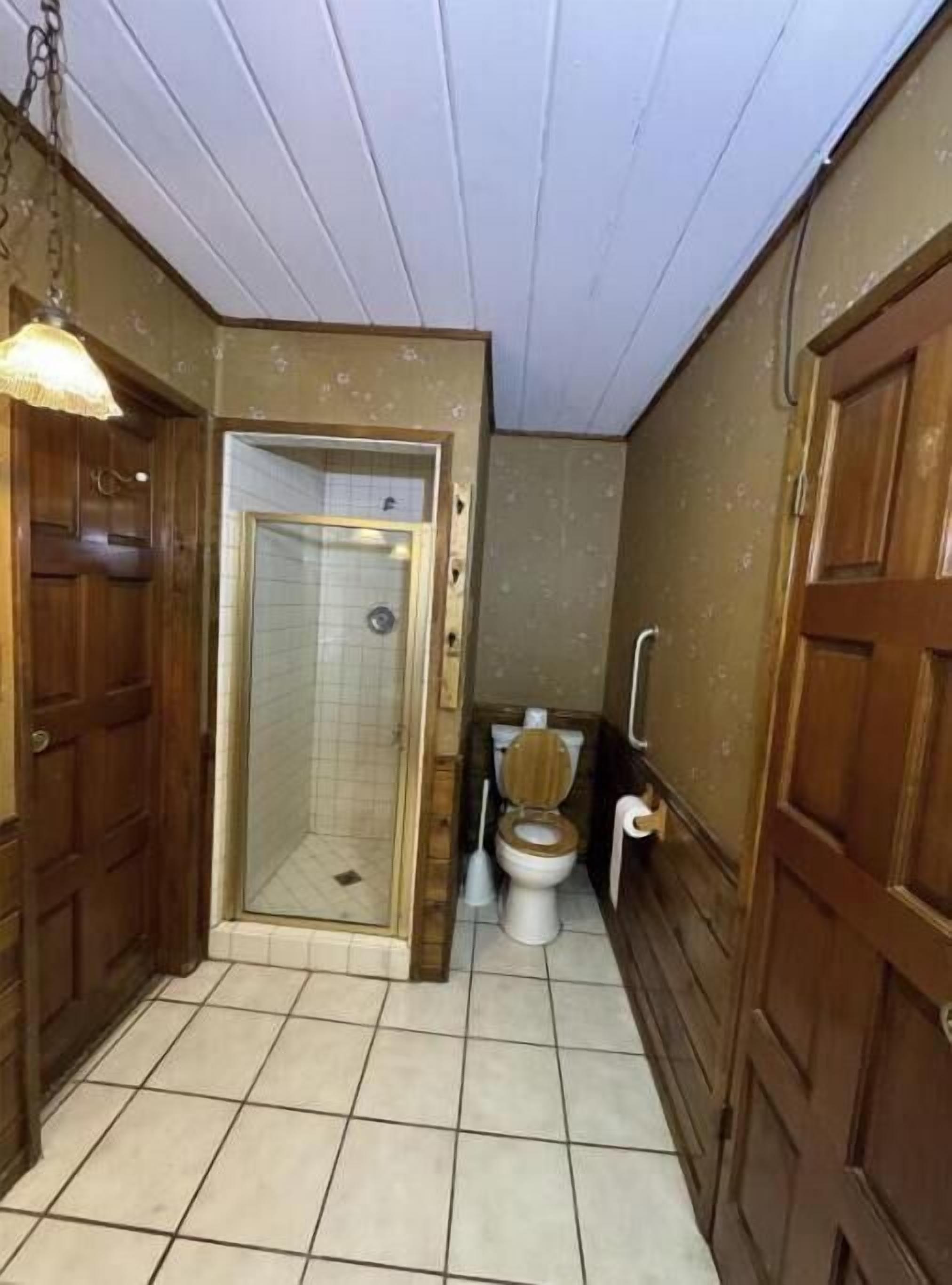 Une petite salle de bain avec douche, toilettes et porte en bois.