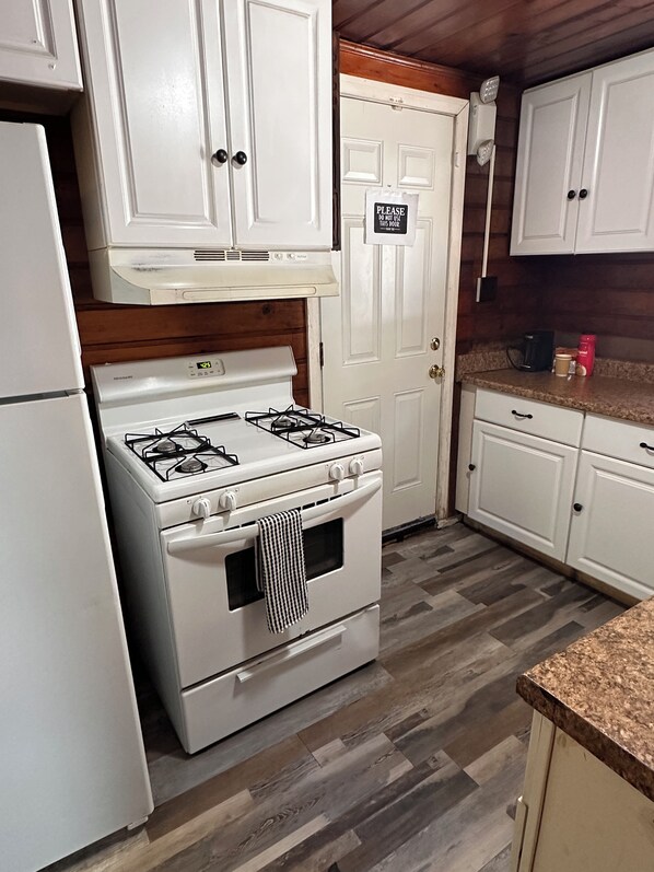A kitchen with white cabinets, a stove, and a refrigerator.