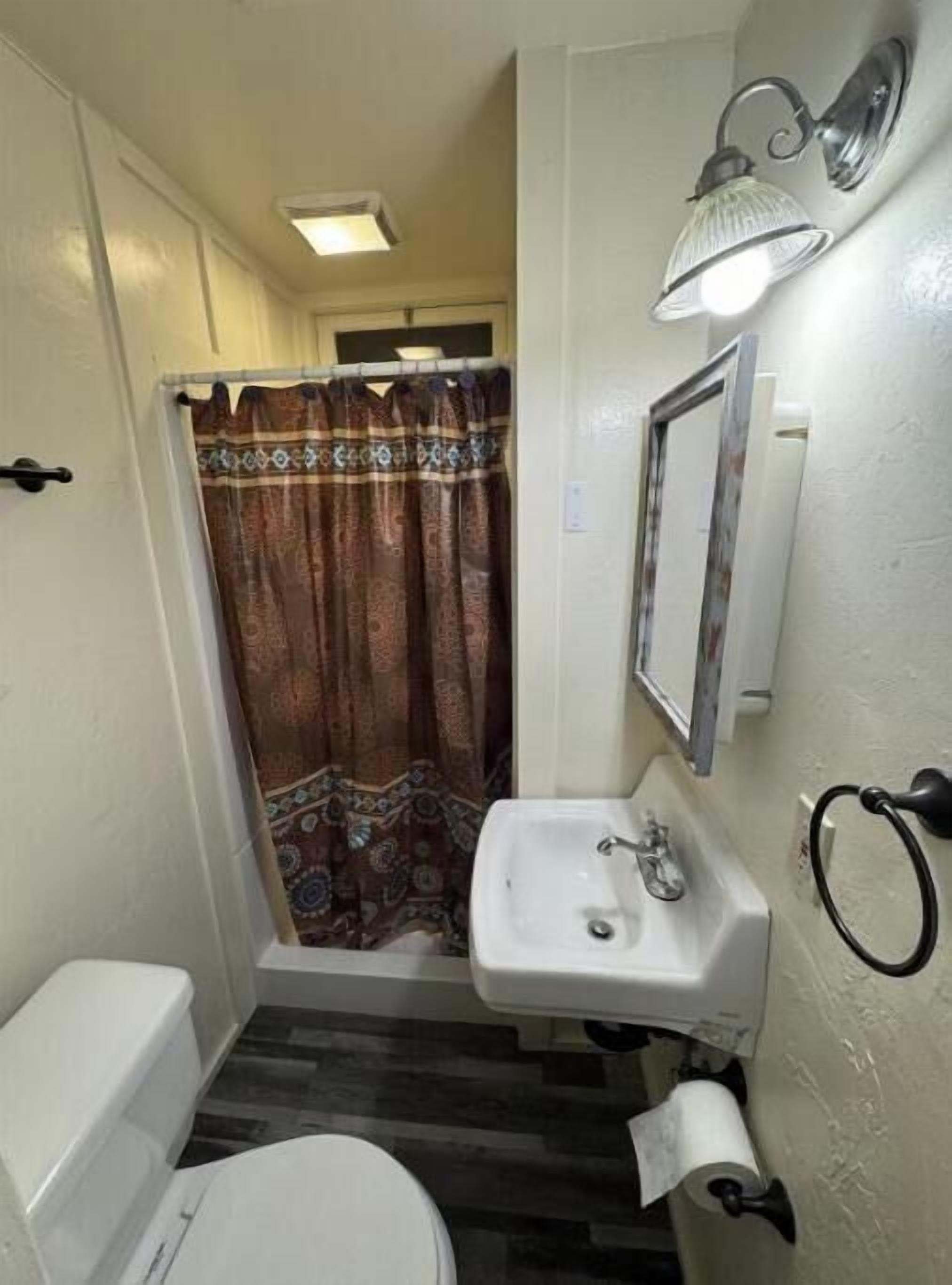 A small bathroom with a toilet, sink, and shower curtain.