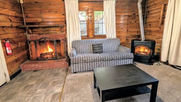 A cozy log cabin interior with a fireplace, a sofa, and a table.