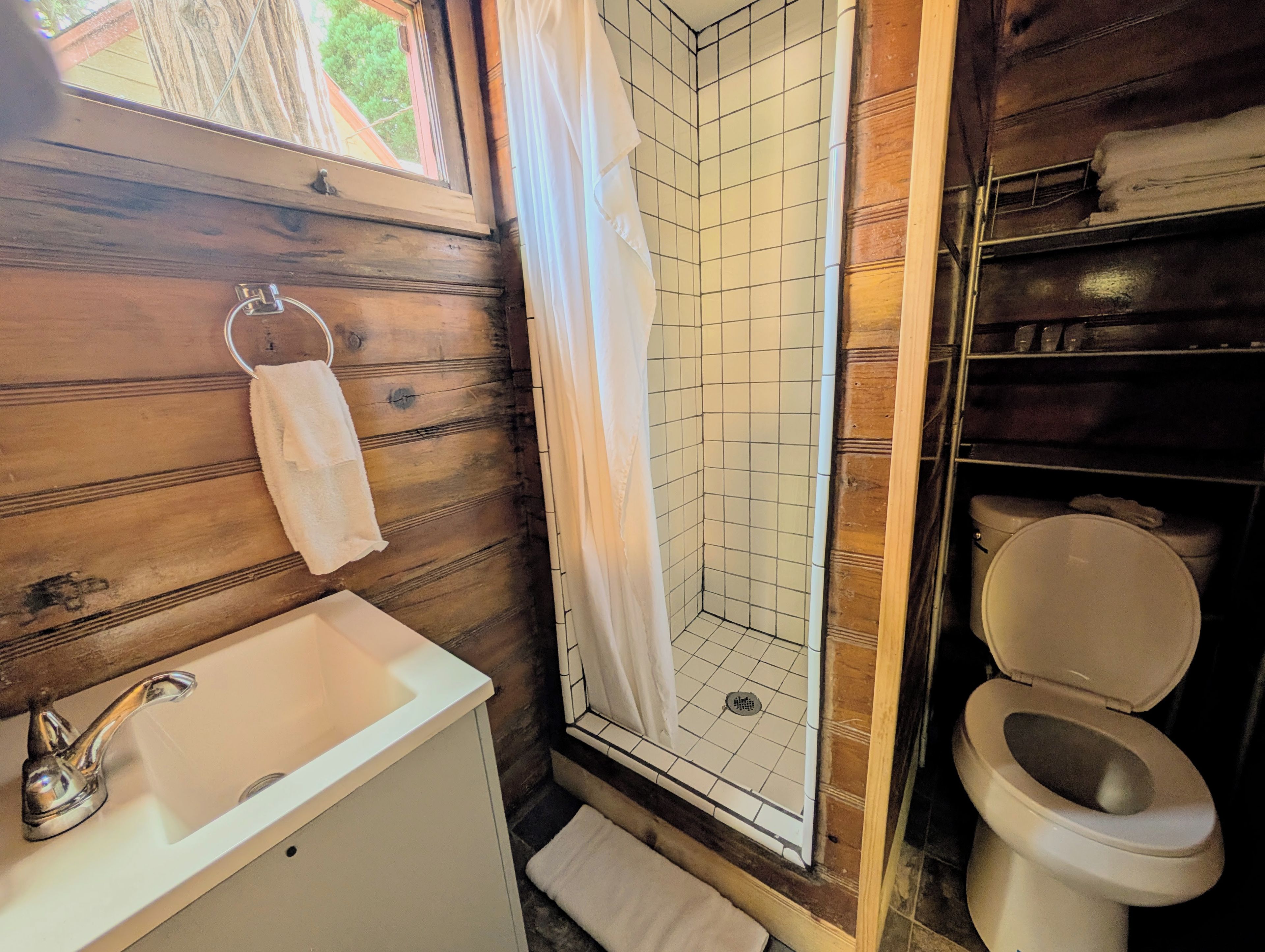 A bathroom with a white sink, a shower with a white curtain, and a toilet.