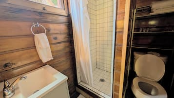 A bathroom with a white sink, a shower with a white curtain, and a toilet.