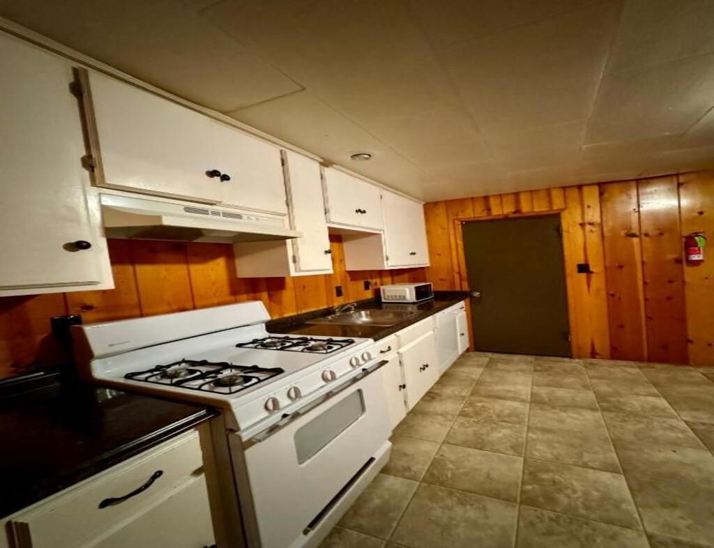 A kitchen with white cabinets, a stove, and a microwave.