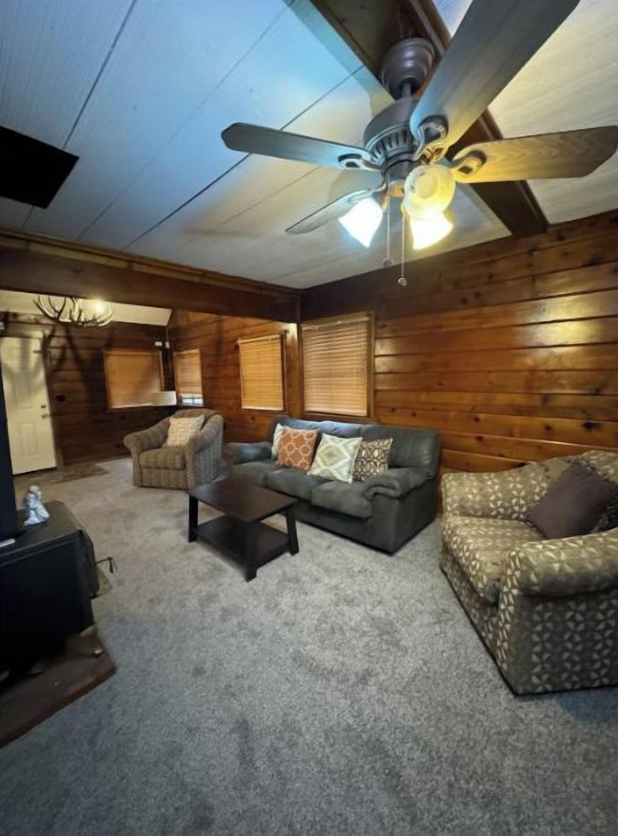 A room with a ceiling fan, a sofa, a chair, and a small table.