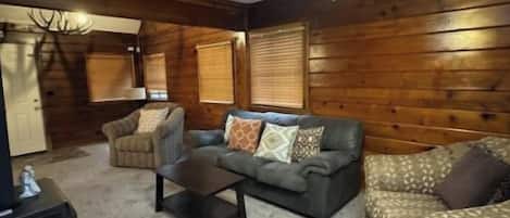 A room with a ceiling fan, a sofa, a chair, and a small table.