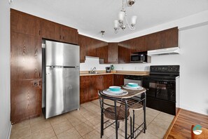 A modern kitchen with wooden cabinets, stainless steel appliances, and a bar stool.