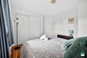 A bedroom with a bed, a wardrobe, a bedside table with a lamp, and a door.