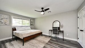 A bedroom with a bed, a desk, a chair, a mirror, and a ceiling fan. - Lake Conroe & Golf Nearby in a Quiet  Area (Conroe)