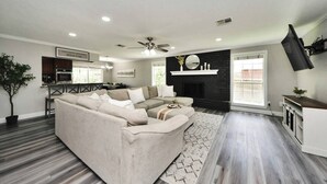 A modern living room with a sectional sofa, a fireplace, and a flat-screen TV. - Lake Conroe & Golf Nearby in a Quiet  Area (Conroe)