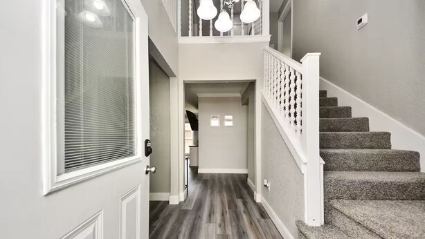 A hallway with a wooden floor, a staircase with a white railing, and a door with a window. - Lake Conroe & Golf Nearby in a Quiet  Area (Conroe)