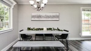 A dining area with a white table, black chairs, a bench, a chandelier, and a framed abstract painting on the wall. - Lake Conroe & Golf Nearby in a Quiet  Area (Conroe)