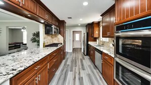 A modern kitchen with wooden cabinets, granite countertops, a stainless steel range, and a built-in oven. - Lake Conroe & Golf Nearby in a Quiet  Area (Conroe)