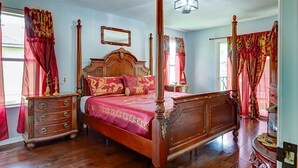 A four-poster bed with a wooden headboard, a nightstand, and a dresser with drawers.