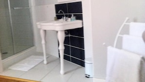 A bathroom with a white pedestal sink, a glass shower enclosure, and a white towel rack. - la  demeure de Laclais (Le Mans)