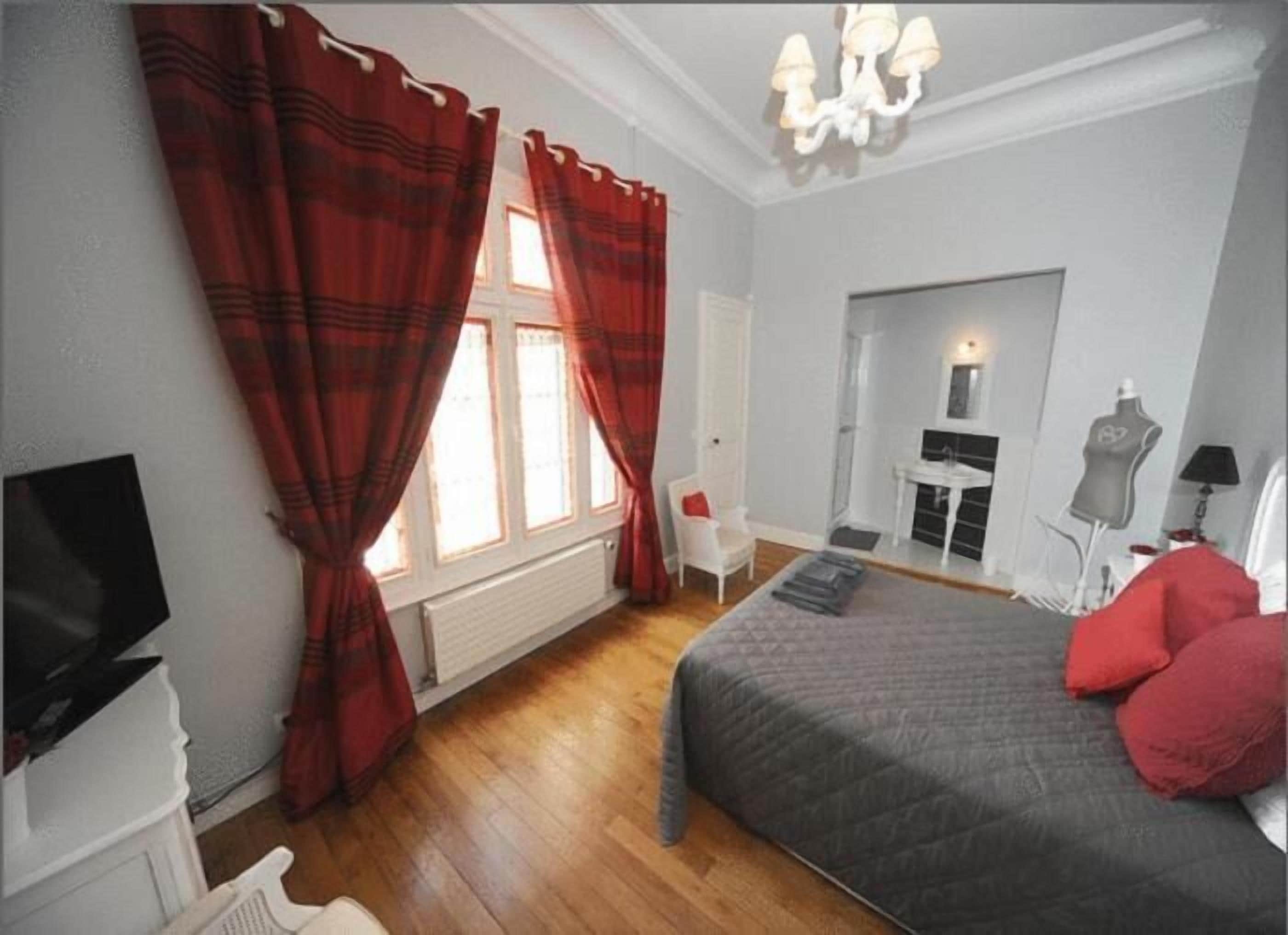 Een slaapkamer met een bed, een televisie, een stoel, een dressoir en een open haard.