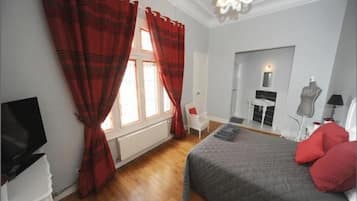 Een slaapkamer met een bed, een televisie, een stoel, een dressoir en een open haard.