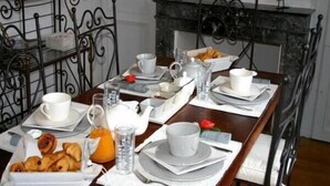 A breakfast table set with plates, cups, a teapot, and a croissant tray. - la  demeure de Laclais (Le Mans)
