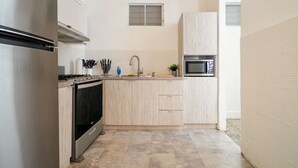 Une cuisine compacte équipée d’un four encastré, d’un four à micro-ondes et d’un petit évier.