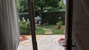 En åben dør til en terrasse med flisegulv, en lille måtte og en plantekasse.