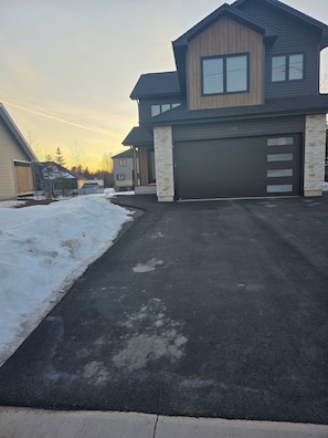 A modern two-story house with a garage, a driveway, and a snow-covered lawn. - FemMac's Place (Moncton)