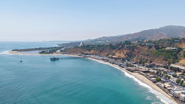 A coastal town with a pier extending into the ocean, a beach, and residential buildings. - Oceanfront Gem w/ Balcony, Pool, Hot Tub & Carbon Beach Access Bluewater Haven by Avantstay (Malibu)