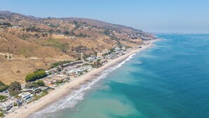 A coastal town with a beach, houses, and hills in the background. - Oceanfront Gem w/ Balcony, Pool, Hot Tub & Carbon Beach Access Bluewater Haven by Avantstay (Malibu)