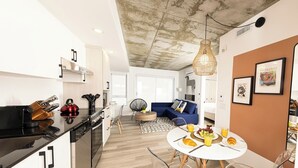 Una cocina moderna con comedor, un sofá azul y una mesa de comedor servida con comida y bebidas.