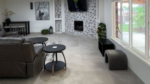 A modern living room with a fireplace, a sofa, a coffee table, and a TV mounted on the wall. - Charming 4-bedroom house with AC in Gallup (Gallup)