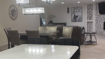 A modern kitchen with a central island, bar stools, pendant lighting, and a dining area with leather seating.