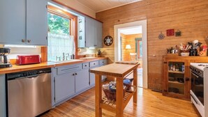 Eine kleine Küche mit Holzausstattung, einem roten Toaster, einer Spüle und einem Holztisch.