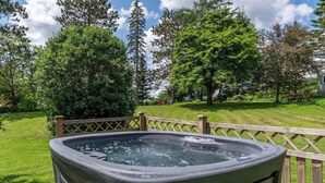 Ein Whirlpool in einem Garten mit Holzzaun und üppiger Bepflanzung.