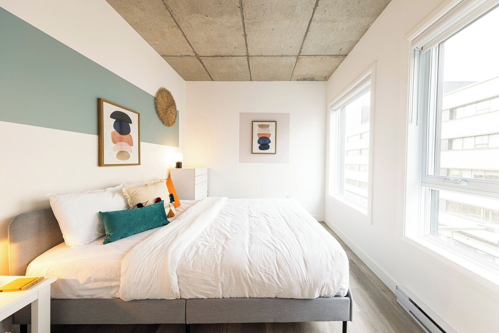 A bedroom with a bed, a bedside table, a lamp, and a window.
