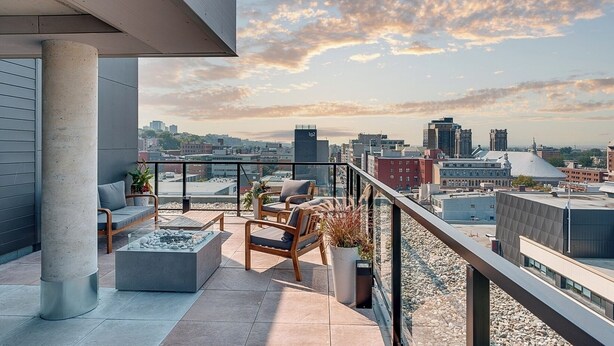 A rooftop terrace with a view of the city skyline, furnished with a sofa, chairs, and a coffee table.