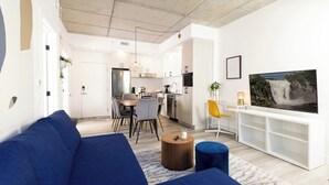 A modern living room with a blue sofa, a round coffee table, and a TV on a white stand.