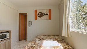 Ein Schlafzimmer mit einem Bett, einer Mikrowelle, einer Tür und einem Fenster mit Blick.