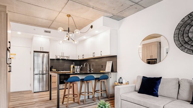 Une cuisine moderne dotée d’un îlot central, de tabourets de bar et d’un coin repas.