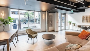 Un interior moderno con comedor, asientos y ventanas amplias que ofrecen vistas a la calle.