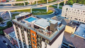 A high-rise building with a rooftop pool, multiple balconies, and a view of the surrounding urban area.