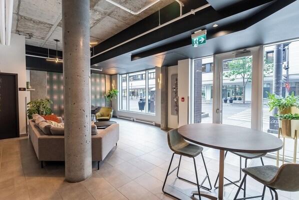 A modern lobby with a round table, bar stools, a sofa, and a large pillar.