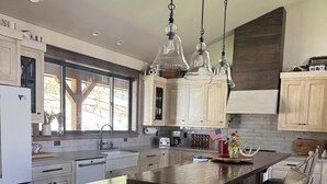 Una cocina moderna con armarios de madera, una isla grande, luces colgantes y vistas por la ventana.
