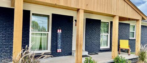 Un edificio moderno con fachada de ladrillo oscuro, columnas de madera y un letrero acogedor.