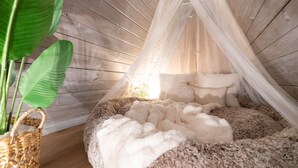 A cozy, rustic room with a wooden ceiling, a fluffy white bed, and a hanging net. - Cozy A-Frame Retreat (Gatlinburg)