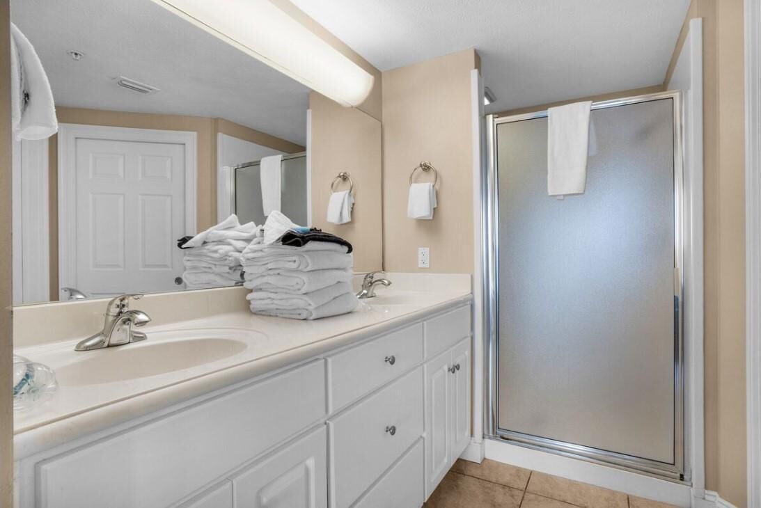 A modern bathroom with a large mirror, a sink, and a shower.
