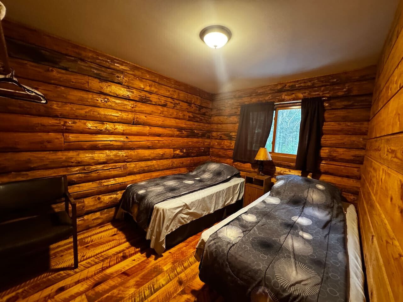 Une cabine équipée de deux lits, d’une chaise et d’une fenêtre avec des rideaux.