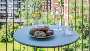 Un balcon avec une table dressée pour deux personnes, agrémenté d’une assiette de pâtisseries et de deux verres de vin blanc.