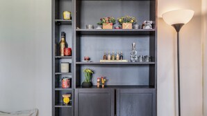 Une étagère en bois foncé, sur laquelle sont disposés divers objets, notamment des bougies, des bouteilles et des objets décoratifs.
