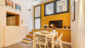 A compact living space with a dining area, a TV mounted on the wall, and a staircase leading to an upper level. - Garibaldi's Gem - La Vista Apartments (Milano)