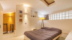 A bedroom with a bed, a bedside table, a lamp, a window with curtains, and a wall-mounted shelf with decorative items. - Garibaldi's Gem - La Vista Apartments (Milano)